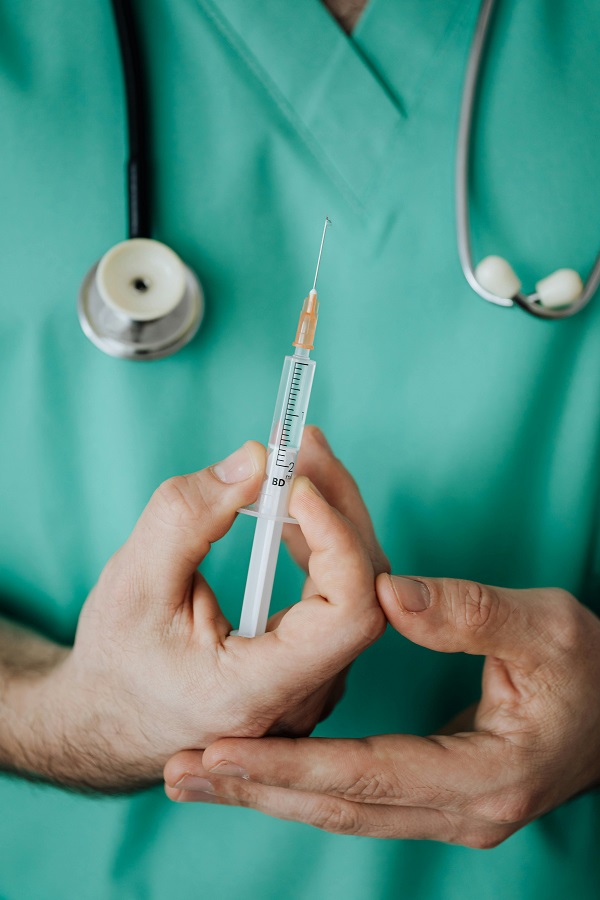 medic in halat verde tine in mana un vaccin